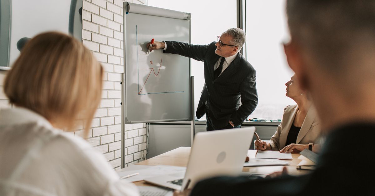 A focused business team engaging in a meeting with a presentation on a whiteboard.
