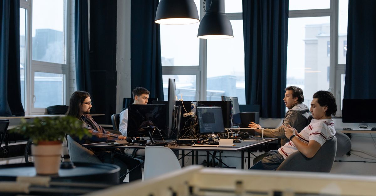 Workers collaborate in a modern office with computers, showcasing teamwork in technology development.