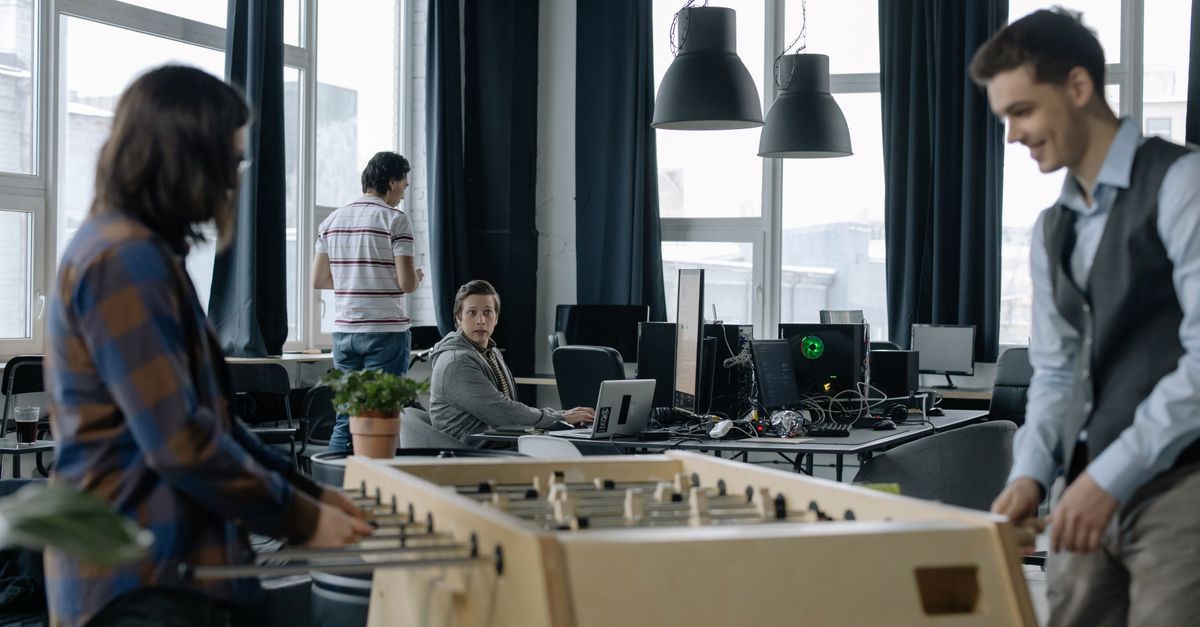 A modern office environment featuring a foosball table with employees engaging in teamwork.