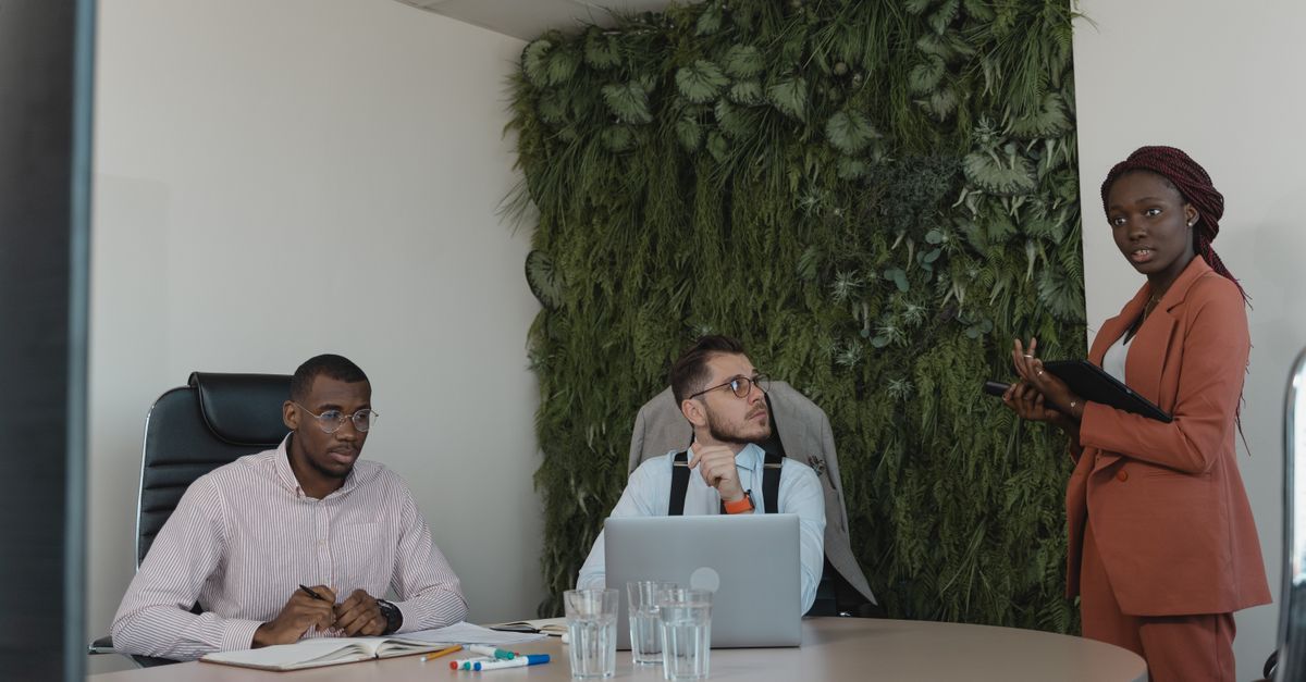A diverse team of professionals engaging in a strategic office meeting with green plants decor.