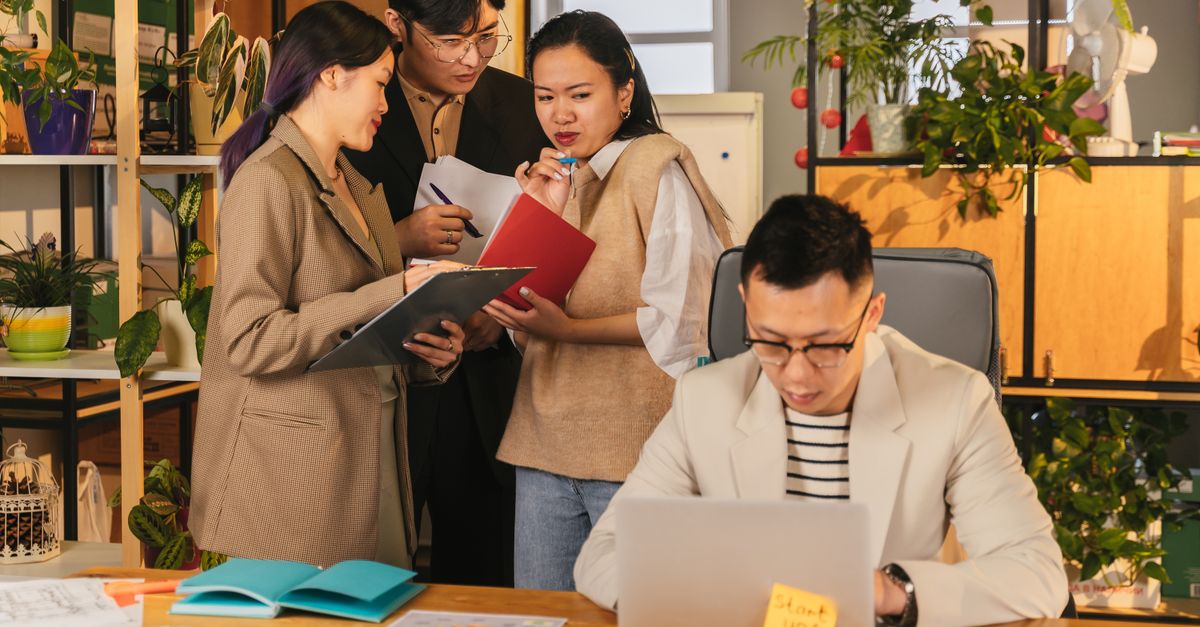 Group of young professionals collaborating in a modern, plant-filled office.